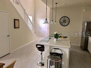 A kitchen island with bar stools sits in a room with tile floors and stairs — 5465 MISTY OAK CIRCLE, DAVENPORT, FL