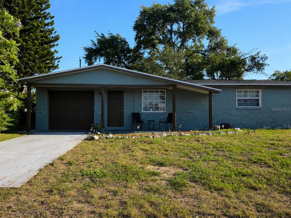 A single-story house with a blue exterior, a front porch, and a concrete driveway — 4823 LONGWOOD AVENUE, HOLIDAY, FL