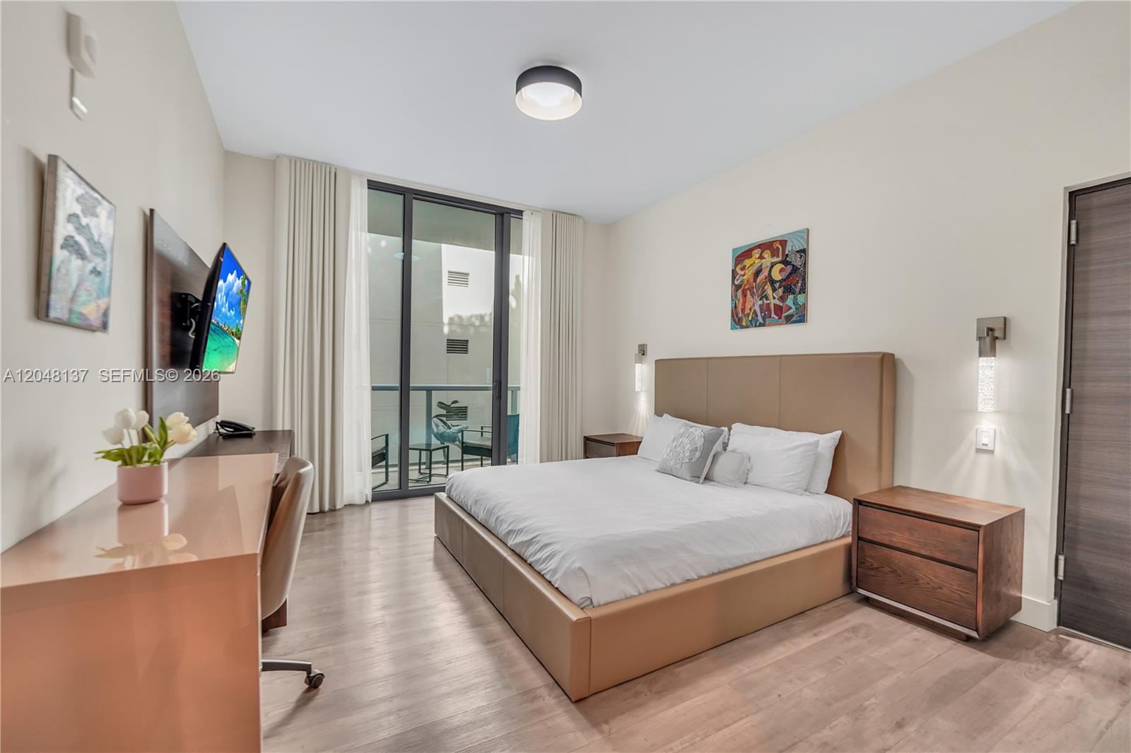 A modern bedroom features a king bed, a desk, and a balcony with outdoor seating — 777 N Ocean Dr # S314, Hollywood FL 33019, HOLLYWOOD, FL