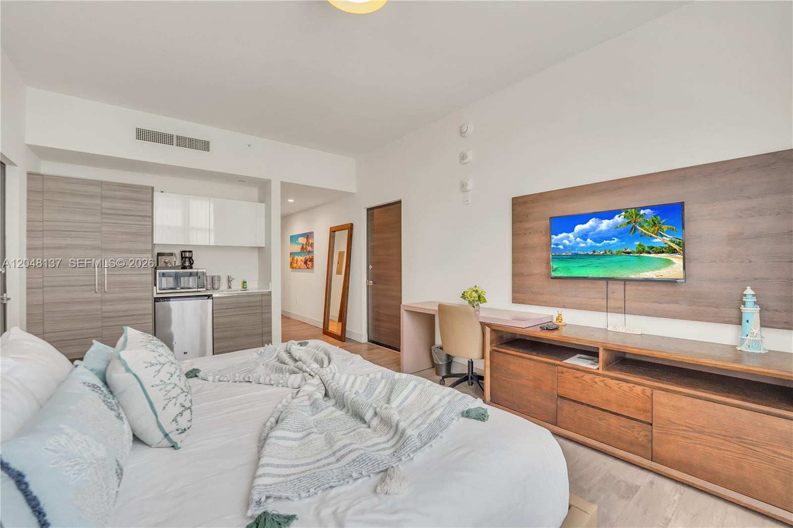 A bedroom features a bed, a small kitchenette, a desk, and a wall-mounted television — 777 N Ocean Dr # S314, Hollywood FL 33019, HOLLYWOOD, FL