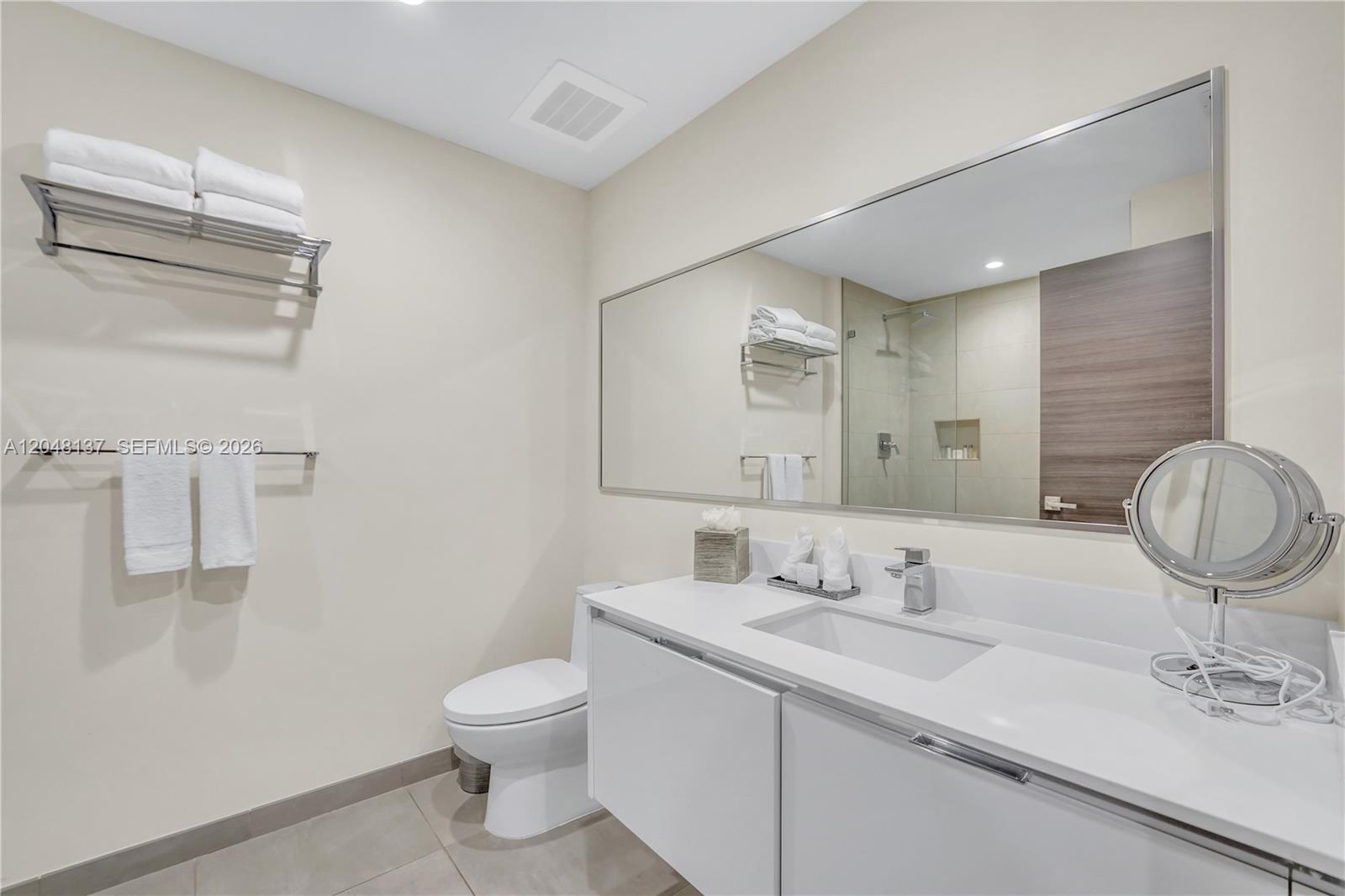 A modern bathroom features a white vanity, a large mirror, and a glass-enclosed shower — 777 N Ocean Dr # S314, Hollywood FL 33019, HOLLYWOOD, FL