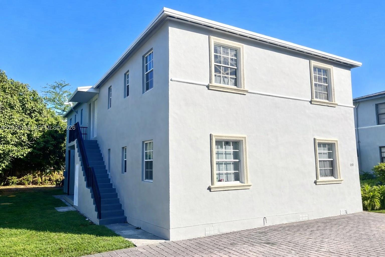 A two-story light gray stucco building features an exterior staircase and a paved driveway — 2371 SW 27th St, Miami FL 33133, MIAMI, FL