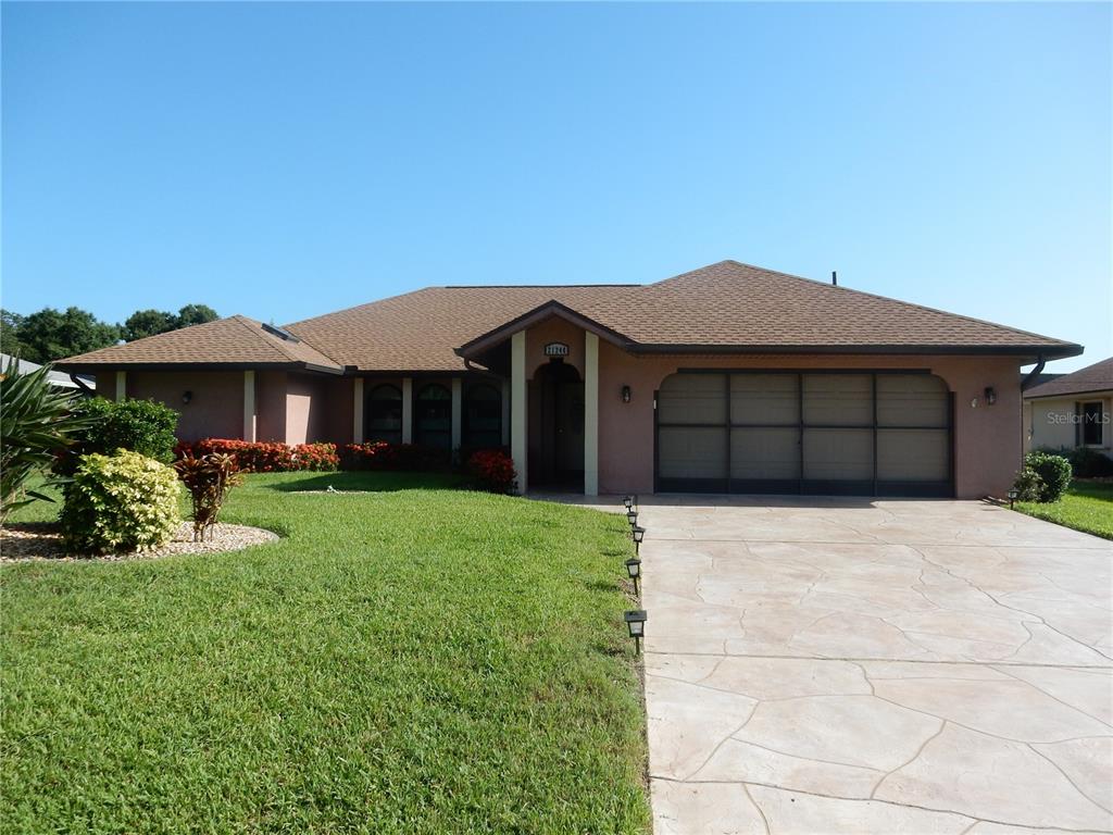 A single-story house with a brown roof, stucco exterior, and a stamped concrete driveway — 21240 CHATBURN AVENUE, PORT CHARLOTTE, FL