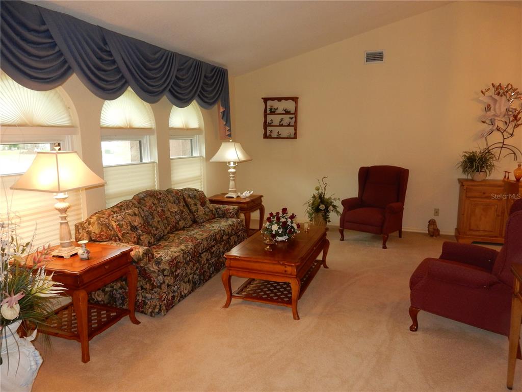 A living room features a floral sofa, two armchairs, a coffee table, and arched windows — 21240 CHATBURN AVENUE, PORT CHARLOTTE, FL