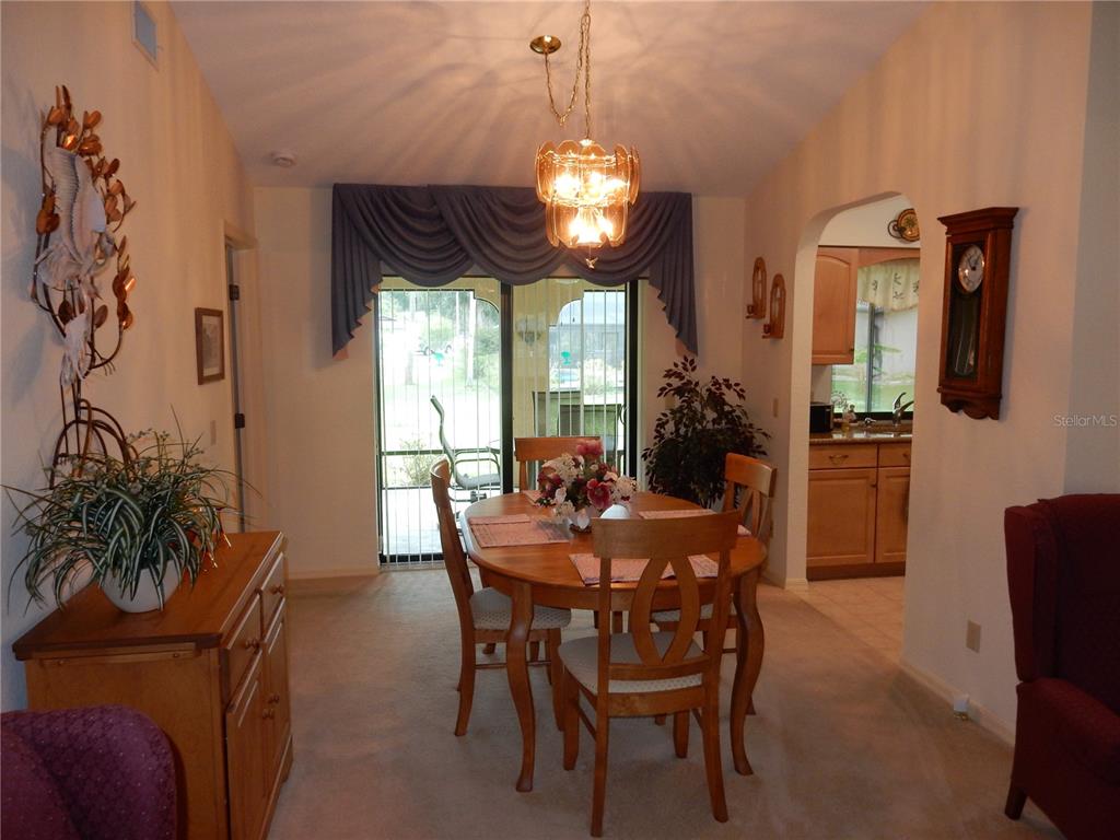 A dining room features a wooden table, chairs, a chandelier, and a sliding glass door — 21240 CHATBURN AVENUE, PORT CHARLOTTE, FL