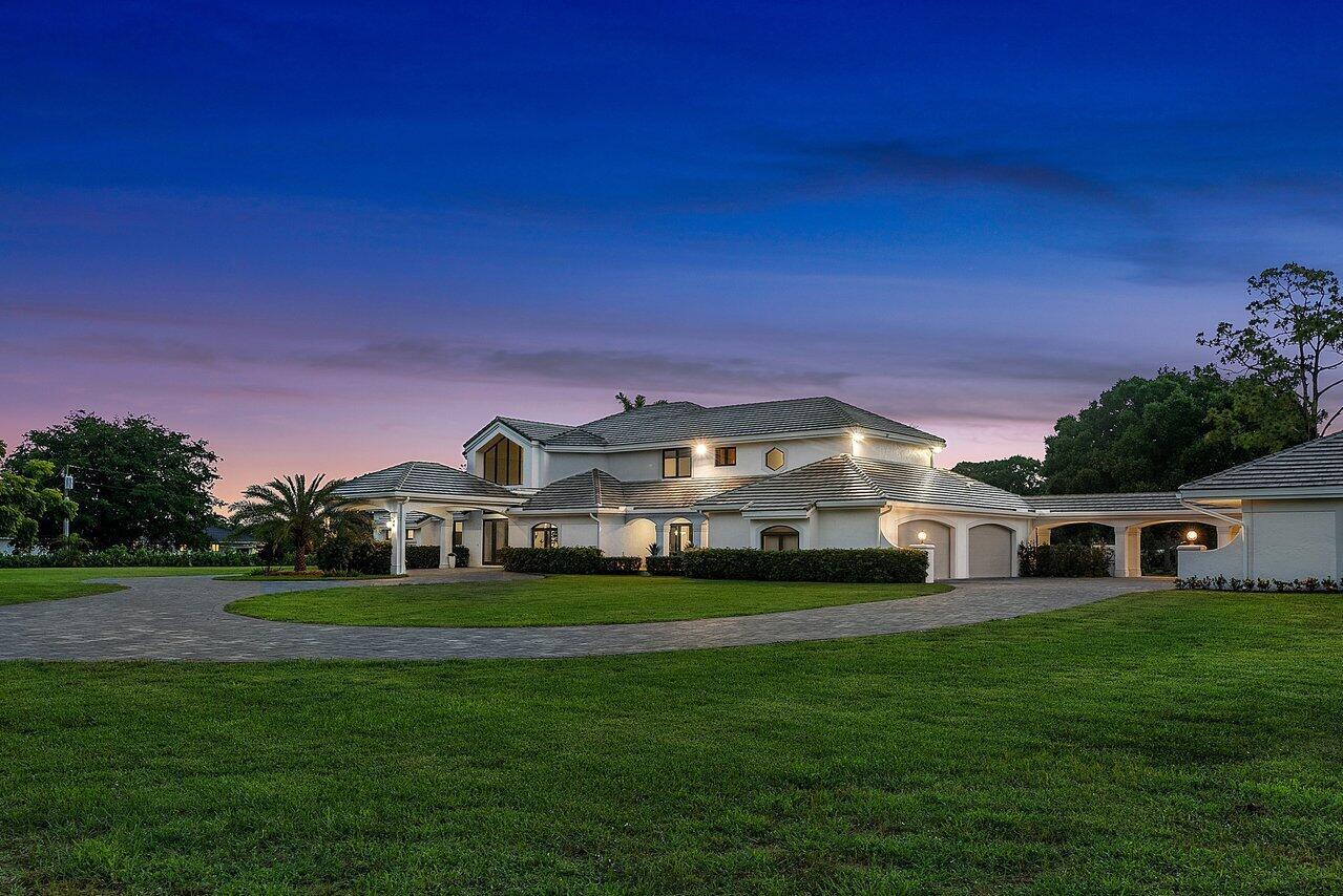 A large, two-story white house with a circular driveway and a tiled roof at dusk — 21677 El Bosque Way, Boca Raton FL 33428, BOCA RATON, FL