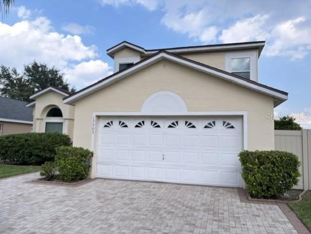 A two-story house features a white garage door, a paved driveway, and manicured landscaping — 13505 MALLARD COVE BLVD, ORLANDO, FL