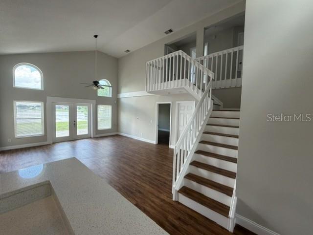 A living area with wood-look flooring, a staircase, and large windows overlooking a lake — 13505 MALLARD COVE BLVD, ORLANDO, FL