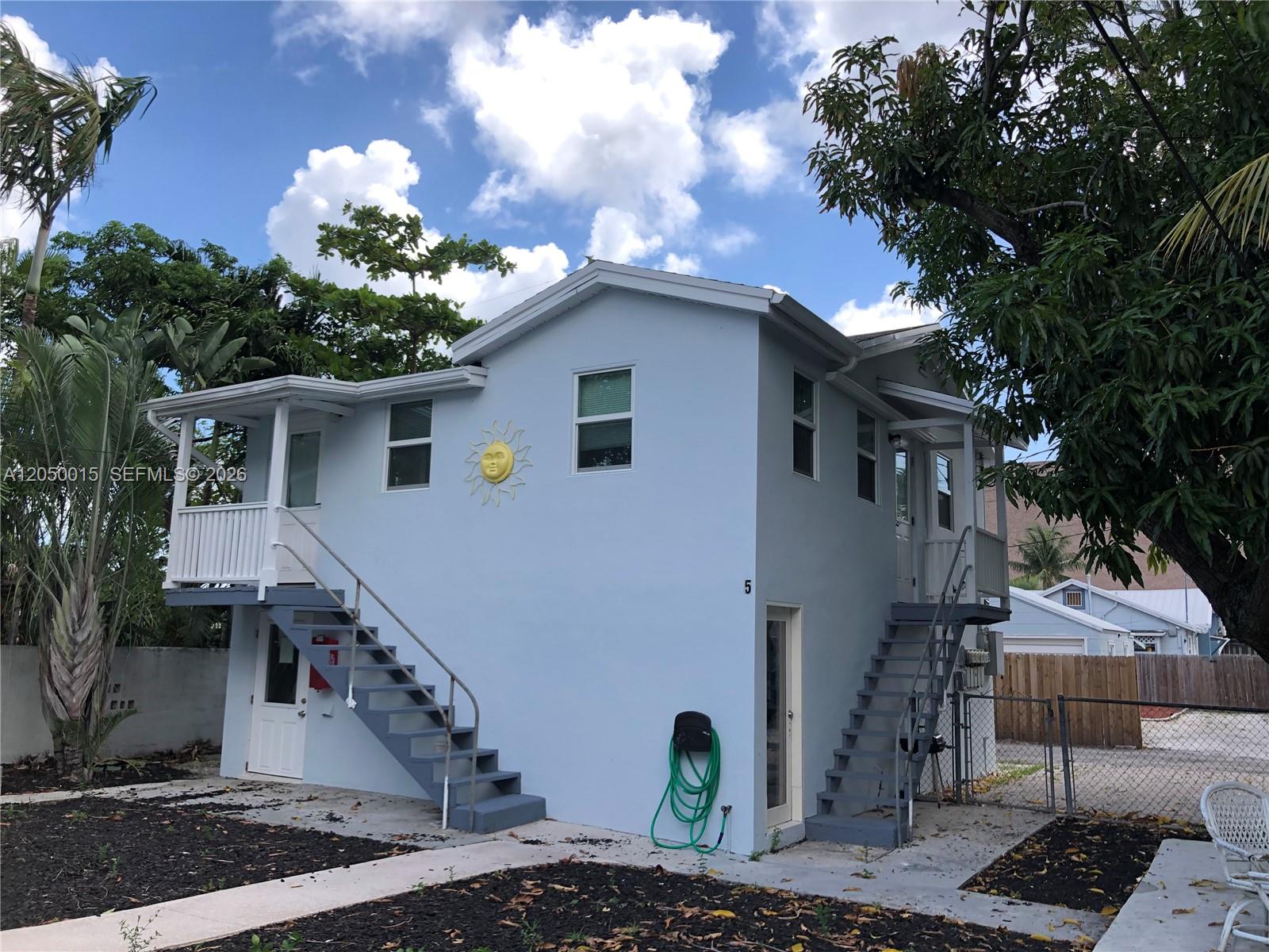 A two-story light blue house features two exterior staircases leading to upper-level entrances — 114 S M St # 5, Lake Worth FL 33460, LAKE WORTH, FL