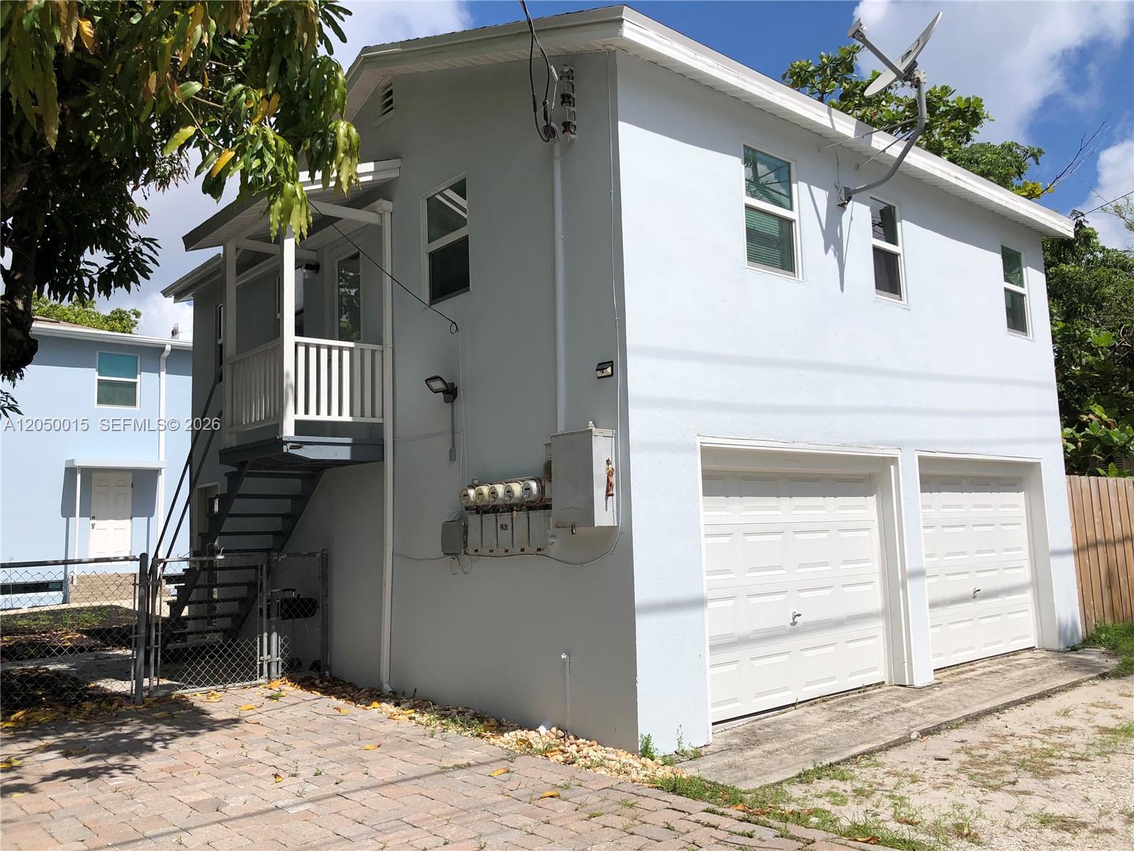 A two-story light blue building features a side staircase, two garage doors, and utility meters — 114 S M St # 5, Lake Worth FL 33460, LAKE WORTH, FL