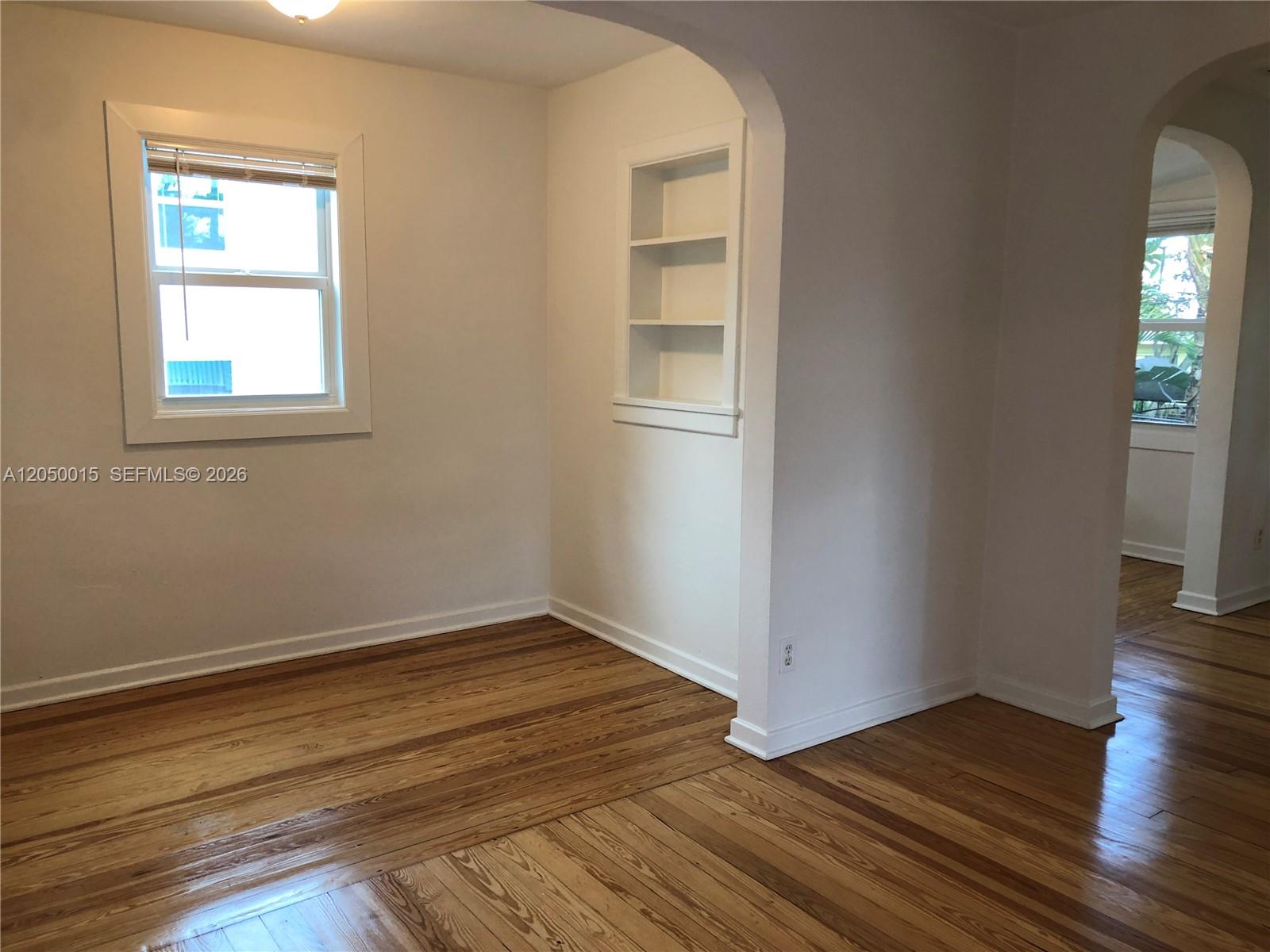 A room with hardwood floors, a window, and built-in wall shelving under an arched doorway — 114 S M St # 5, Lake Worth FL 33460, LAKE WORTH, FL