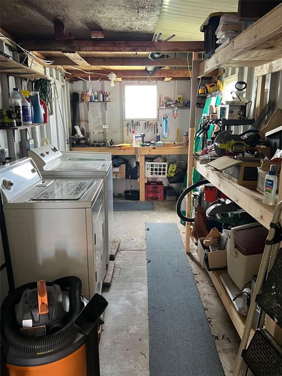 A utility room features a washer and dryer, wooden shelving, and a workbench with tools — 12651 SEMINOLE BOULEVARD UNIT 55, LARGO, FL