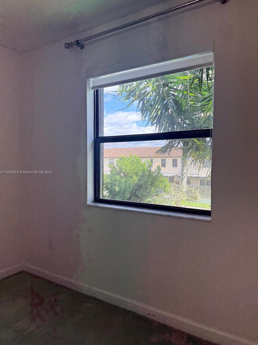 A bedroom features a single window with a view of neighboring buildings and palm trees — 12715 SW 230th Ter, Miami FL 33170, MIAMI, FL