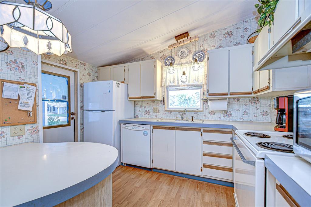 A kitchen features white cabinets, floral wallpaper, a white refrigerator, and a laminate countertop — 3922 WILLIAM HUME DRIVE, ZEPHYRHILLS, FL