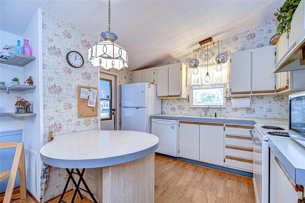 A kitchen with floral wallpaper, white cabinets, a round island, and a hanging pendant light — 3922 WILLIAM HUME DRIVE, ZEPHYRHILLS, FL