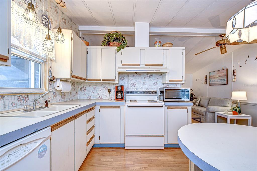 A kitchen with white cabinets, a white stove, and floral wallpaper above the counters — 3922 WILLIAM HUME DRIVE, ZEPHYRHILLS, FL