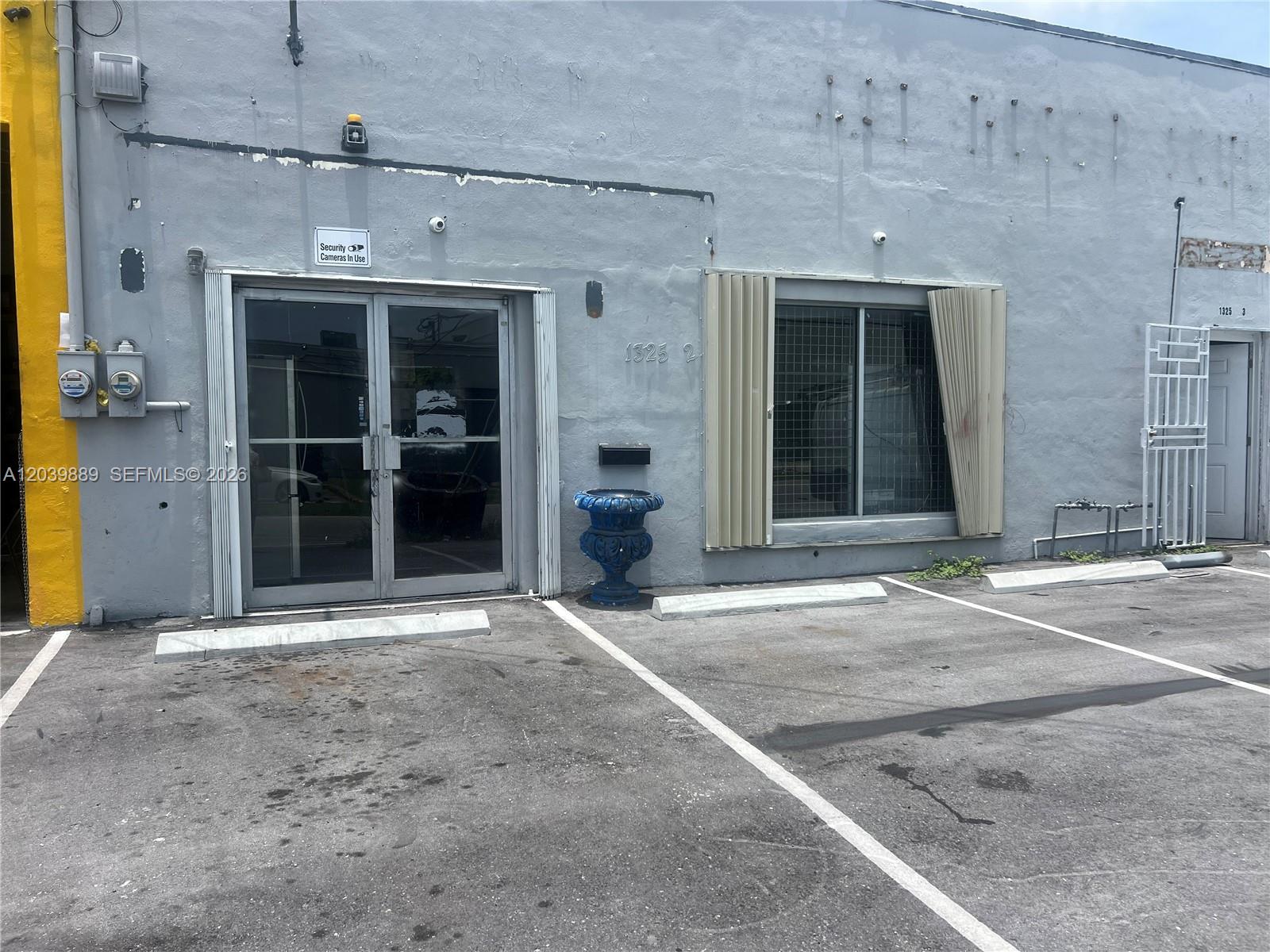The exterior of a gray commercial building features a glass entrance door and a window — 1325 E 10th Ave # 2, Hialeah FL 33010, HIALEAH, FL