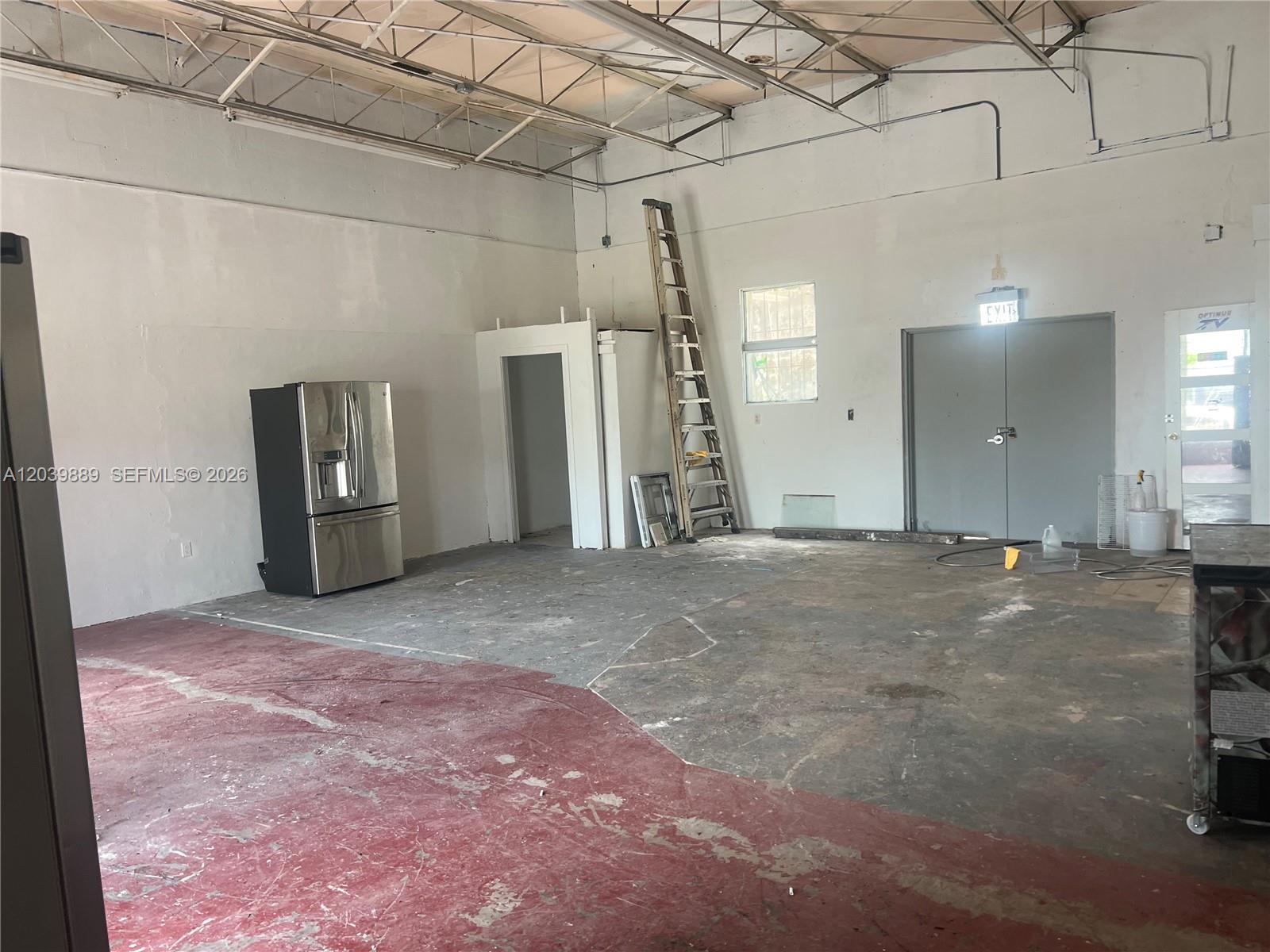 An industrial-style room features a concrete floor, a stainless steel refrigerator, and a tall ladder — 1325 E 10th Ave # 2, Hialeah FL 33010, HIALEAH, FL