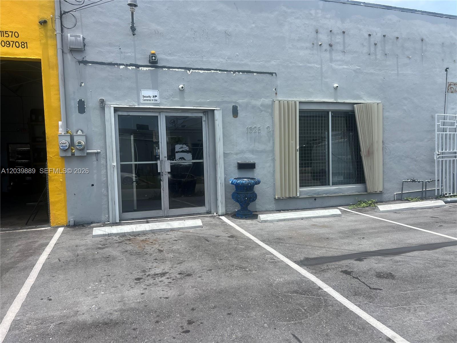 A gray commercial building exterior features a glass double door and a window with shutters — 1325 E 10th Ave # 2, Hialeah FL 33010, HIALEAH, FL