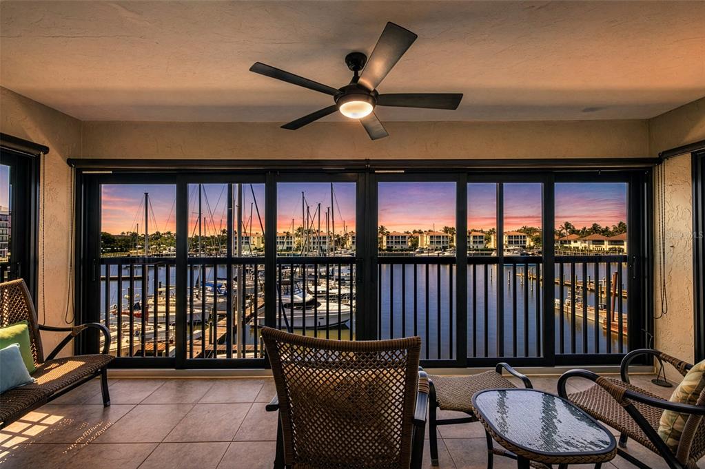 A sunroom with tile floors and a ceiling fan overlooks a marina at sunset — 3235 SUGARLOAF KEY ROAD UNIT 13C, PUNTA GORDA, FL