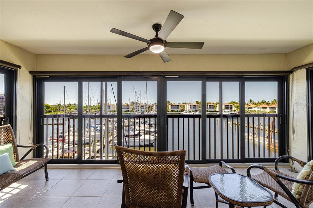 A sunroom with wicker furniture and a ceiling fan overlooks a marina with docked boats — 3235 SUGARLOAF KEY ROAD UNIT 13C, PUNTA GORDA, FL