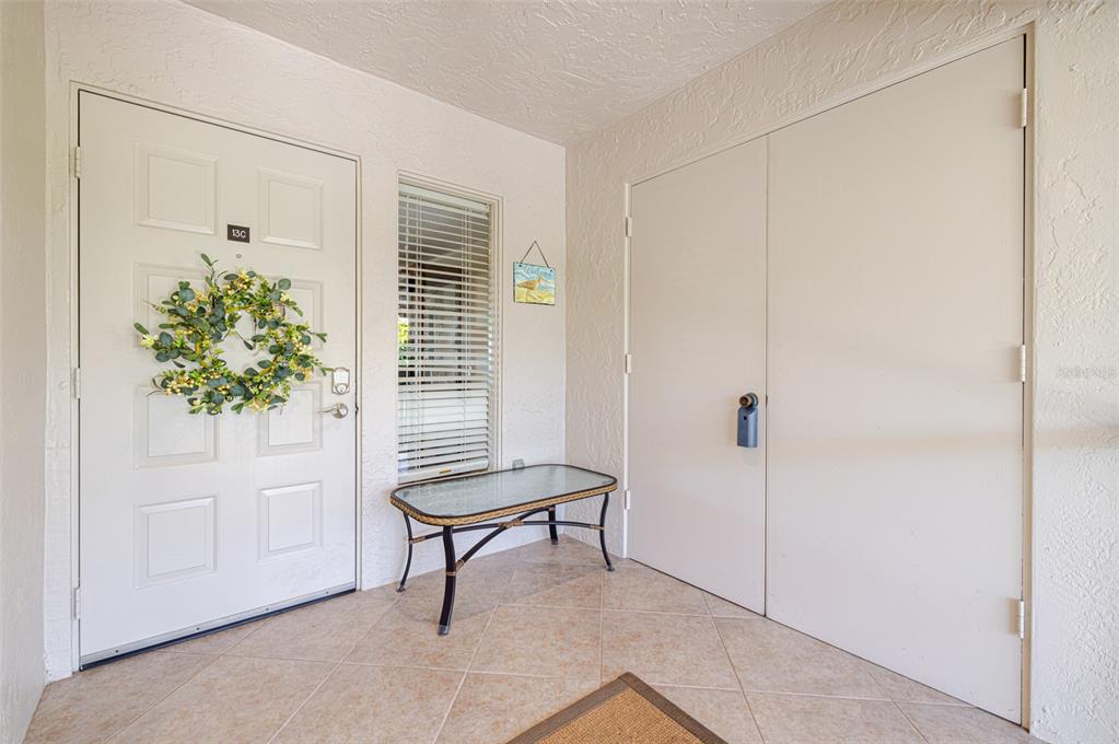 A tiled entryway features a white front door with a wreath, a window, and a bench — 3235 SUGARLOAF KEY ROAD UNIT 13C, PUNTA GORDA, FL