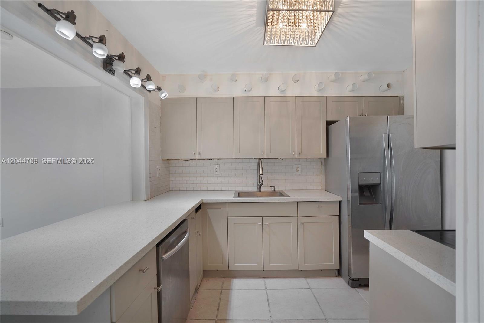 A kitchen features light-colored cabinets, stainless steel appliances, white countertops, and a subway tile backsplash — 6900 Bay Dr # 3H, Miami Beach FL 33141, MIAMI BEACH, FL