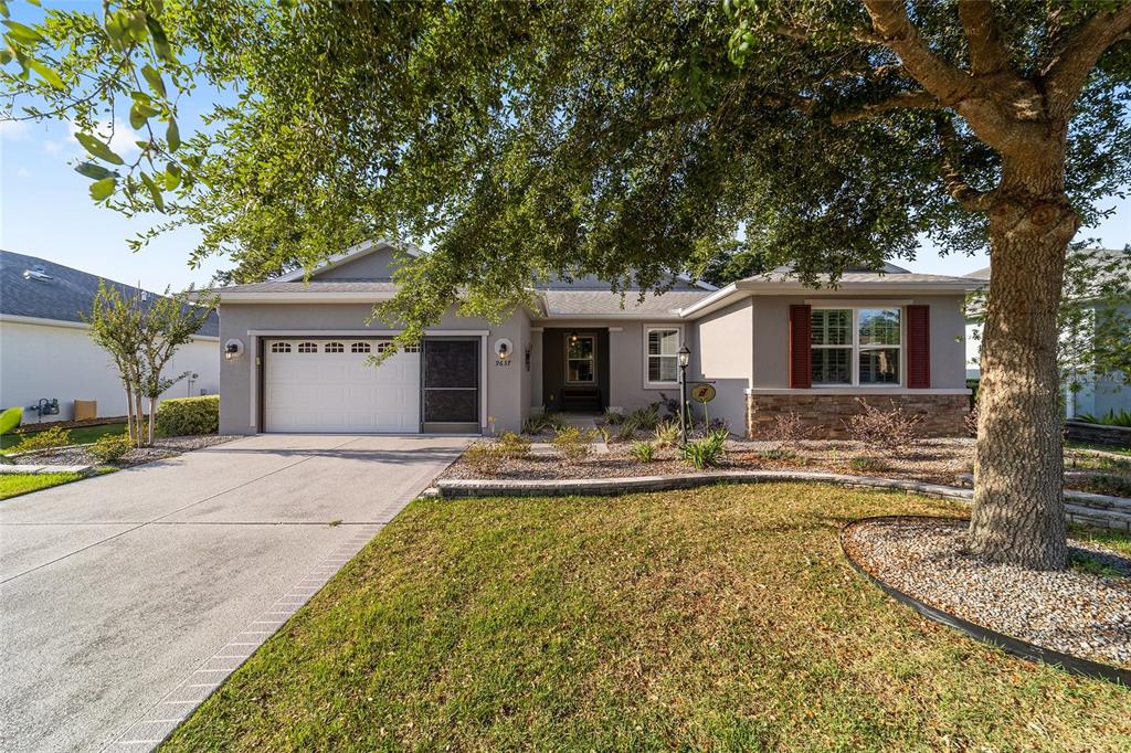A single-story house with a two-car garage, stone accents, and a large tree in front — 9637 SW 95TH LOOP, OCALA, FL