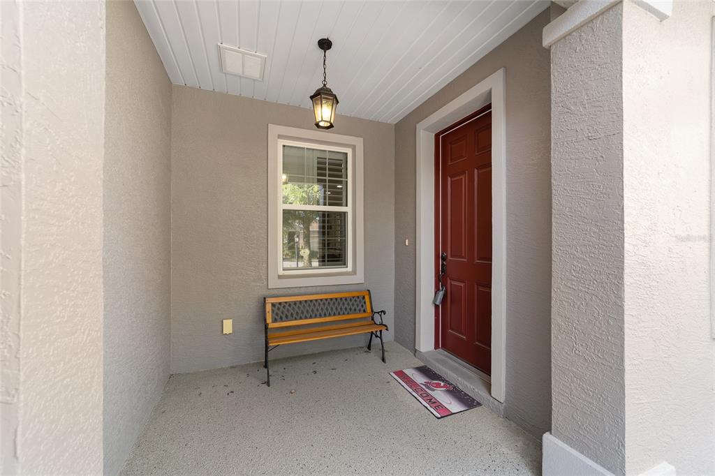 A covered front porch features a wooden bench, a red door, and a hanging light — 9637 SW 95TH LOOP, OCALA, FL
