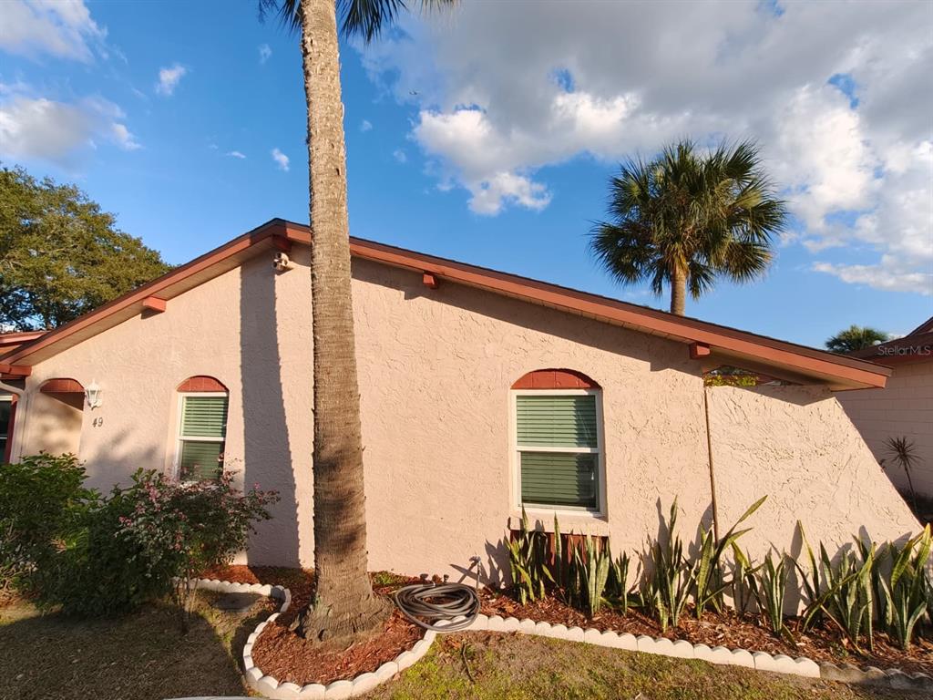 A single-story house with stucco walls, arched windows, and a palm tree in the front yard — 49 W MARBRISA WAY, KISSIMMEE, FL