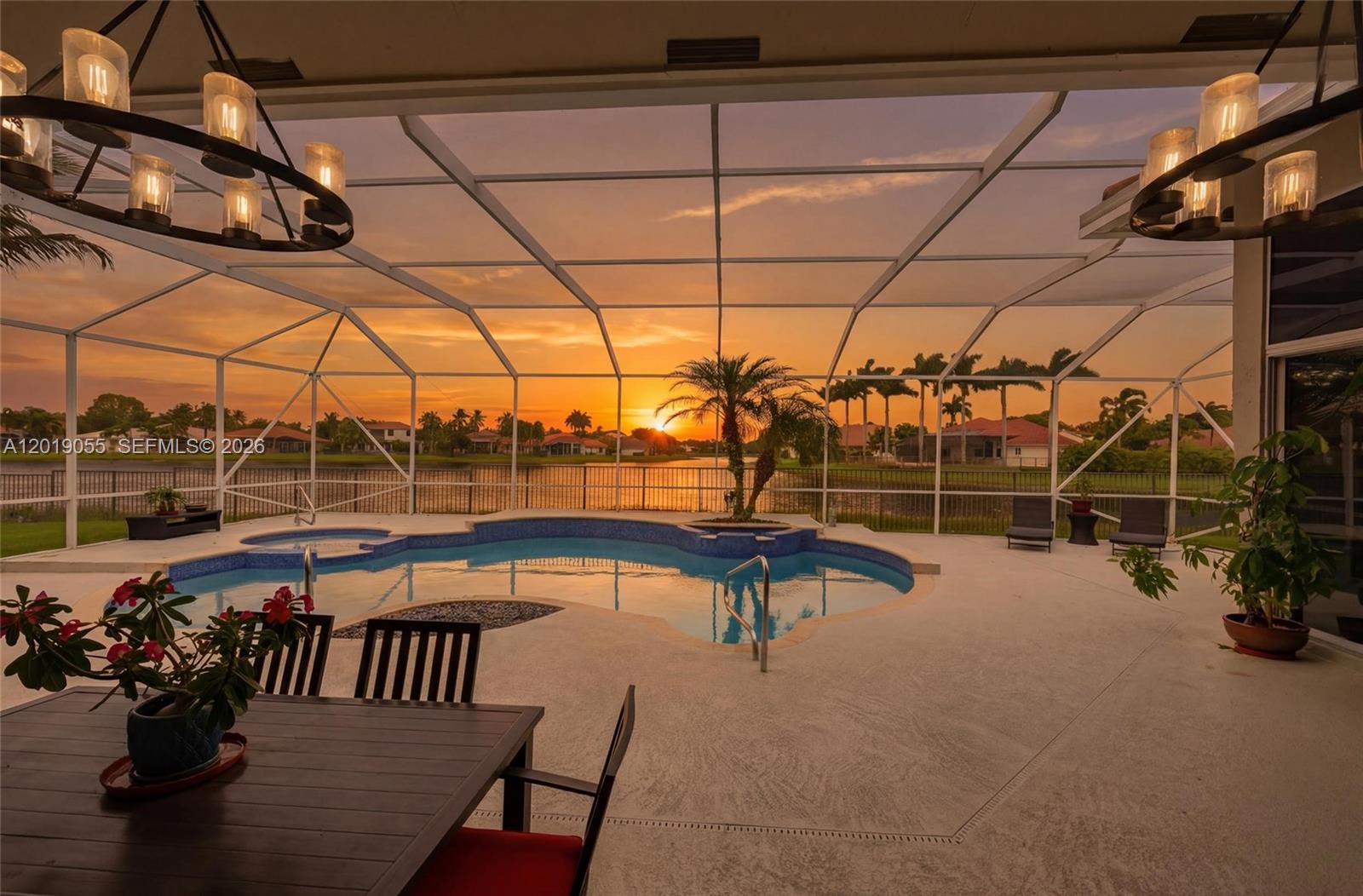 A screened-in patio features a swimming pool, dining area, and sunset views over a lake — 2926 Medinah, Weston FL 33332, WESTON, FL