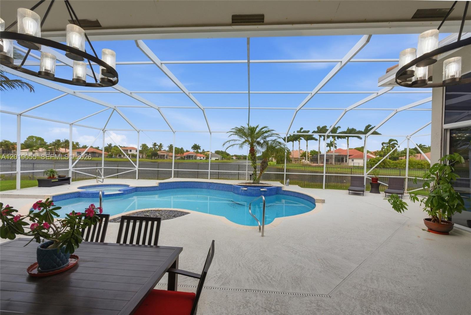 A covered patio overlooks a swimming pool with a spa and a lake view — 2926 Medinah, Weston FL 33332, WESTON, FL