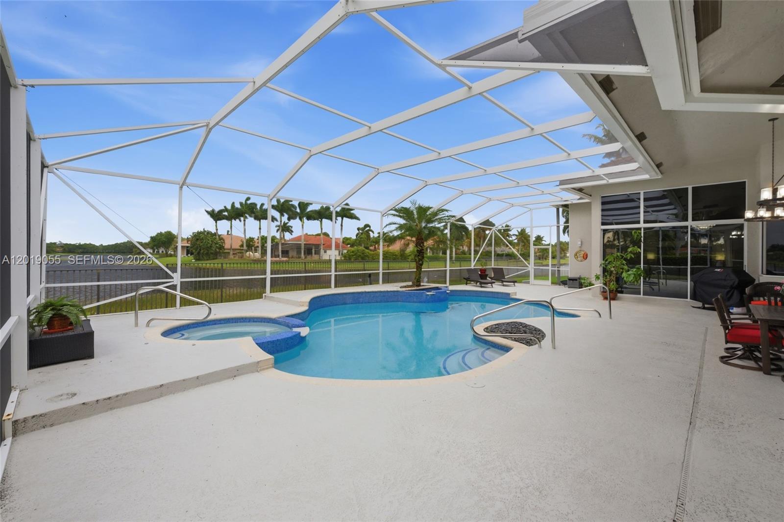 A screened-in patio features a swimming pool, a hot tub, and a view of a lake — 2926 Medinah, Weston FL 33332, WESTON, FL