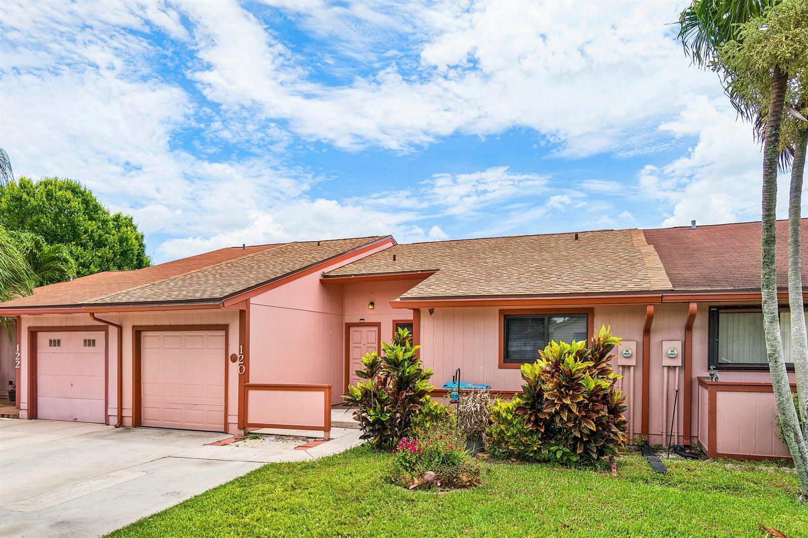 A pink, single-story attached house with a garage, a front door, and landscaping — 120 Mayfair Lane, Boynton Beach FL 33426, BOYNTON BEACH, FL