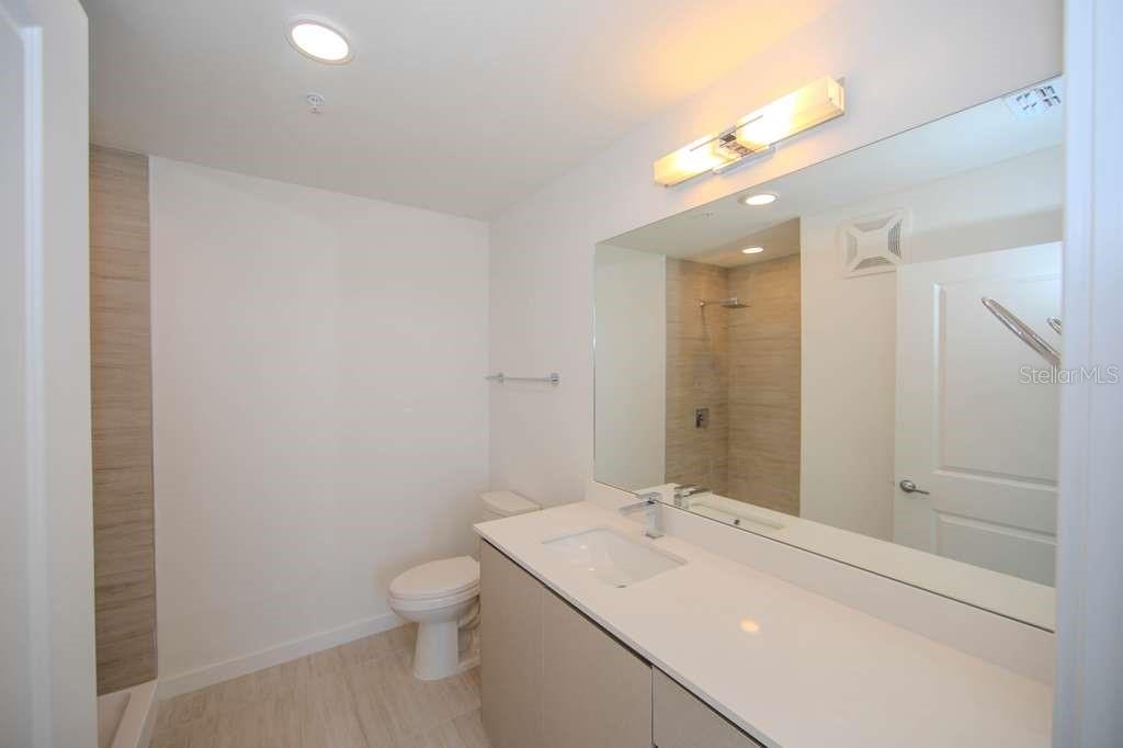 A modern bathroom featuring a vanity with a white countertop, a mirror, and a shower — 5579 MILLENIA PARK BLVD UNIT 511, ORLANDO, FL