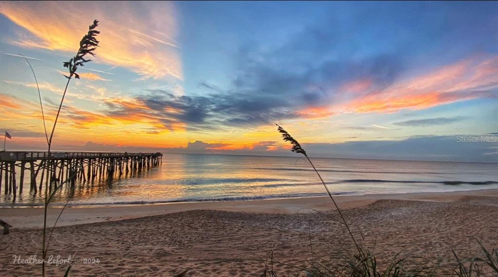 A wooden pier extends into the ocean at sunrise under a colorful, cloudy sky — 1436 S FLAGLER AVENUE, FLAGLER BEACH, FL