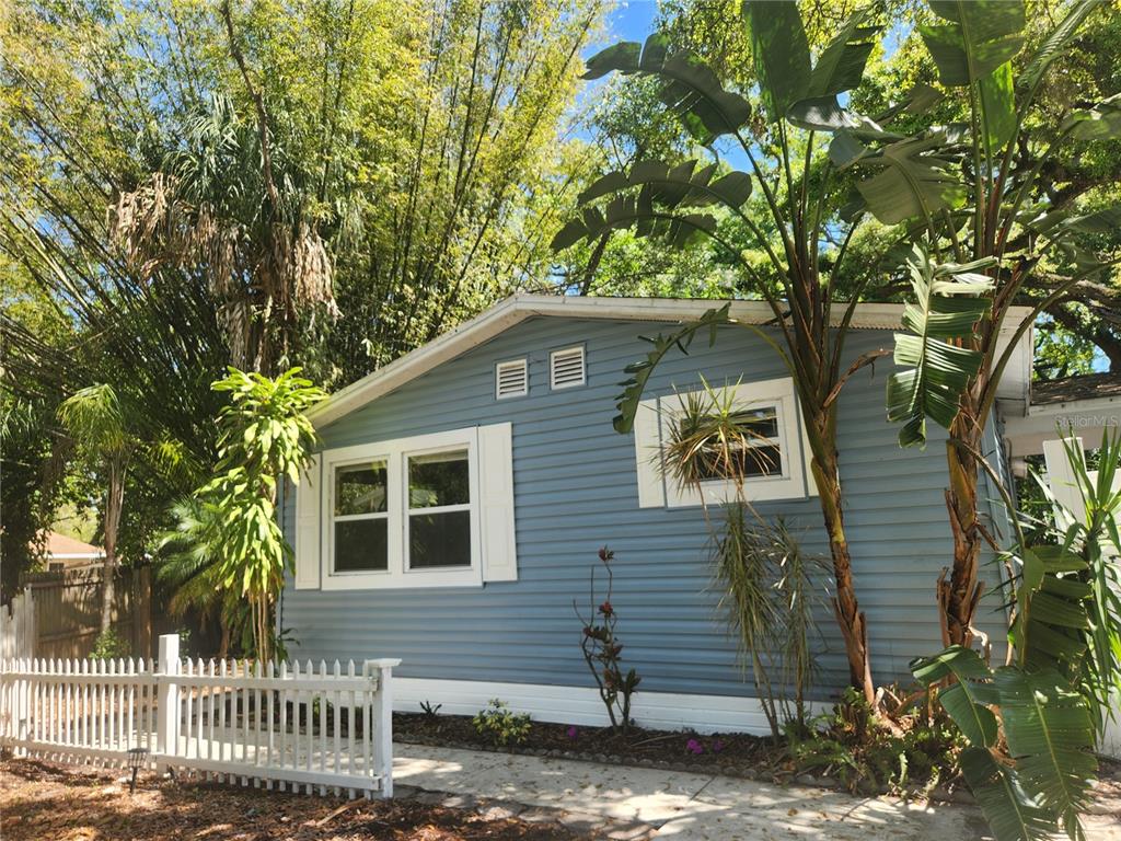 A blue-sided house with white trim and shutters sits behind a white picket fence — 504 BELMONT STREET, SAFETY HARBOR, FL