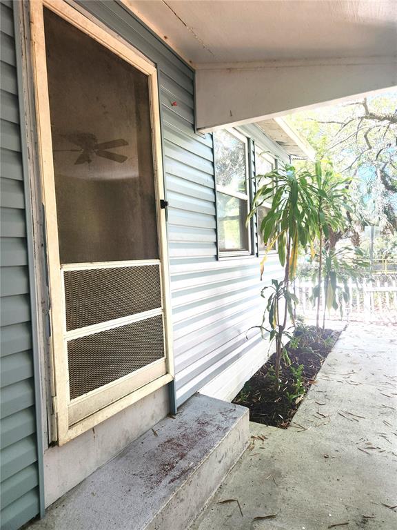 A light blue vinyl-sided exterior wall features a screen door and a small garden bed — 504 BELMONT STREET, SAFETY HARBOR, FL