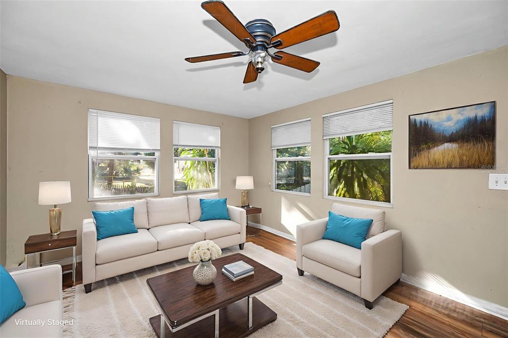 A living room with a sofa, armchair, coffee table, and ceiling fan on wood flooring — 504 BELMONT STREET, SAFETY HARBOR, FL