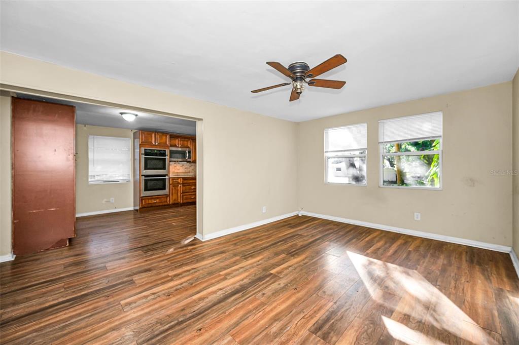 A living room with wood-look flooring, a ceiling fan, and an adjacent kitchen — 504 BELMONT STREET, SAFETY HARBOR, FL