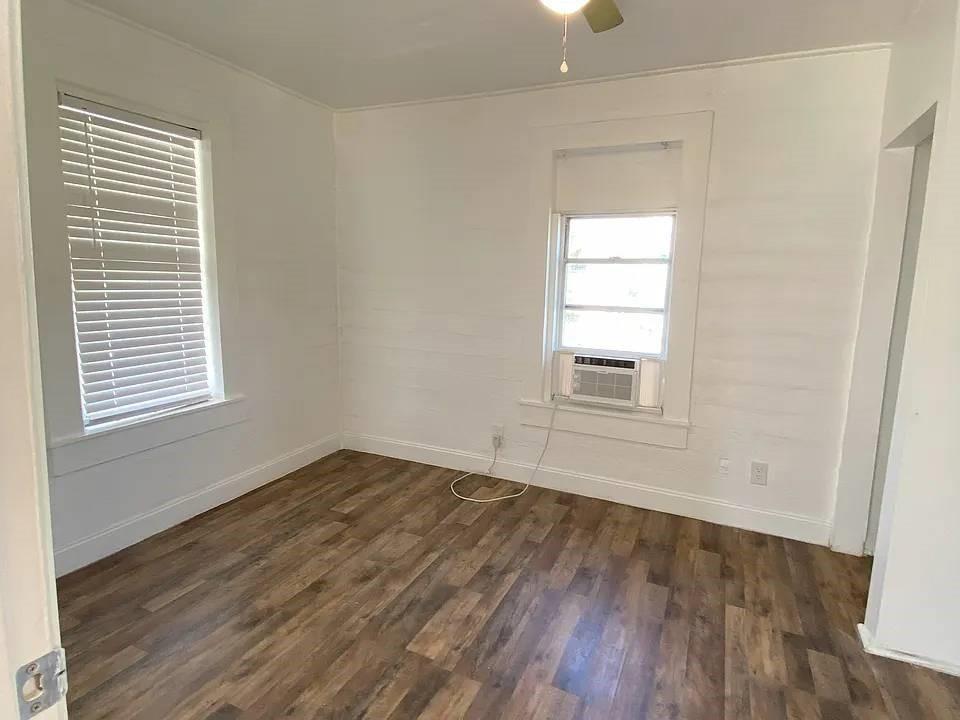 An empty room with white walls, wood-look flooring, two windows, and a window air conditioner — 4144 Herring Avenue, FL 32448, FL