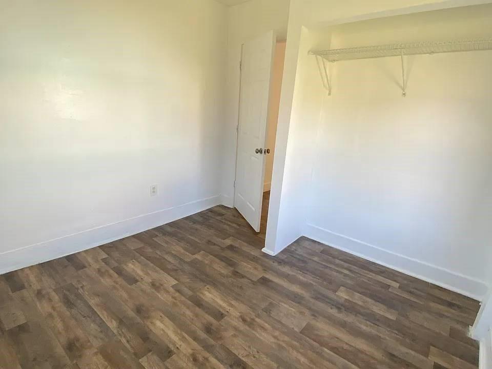 A bedroom with white walls, wood-look flooring, and an open closet with a wire shelf — 4144 Herring Avenue, FL 32448, FL