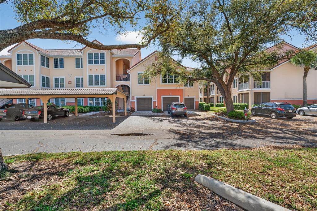 Exterior view of a multi-story apartment complex with a covered parking area and garages — 4138 CENTRAL SARASOTA PARKWAY UNIT 1526, SARASOTA, FL