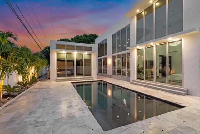 A modern white house with large glass windows overlooks a rectangular swimming pool and patio — 284 NE 7th Street, Boca Raton FL 33432, BOCA RATON, FL