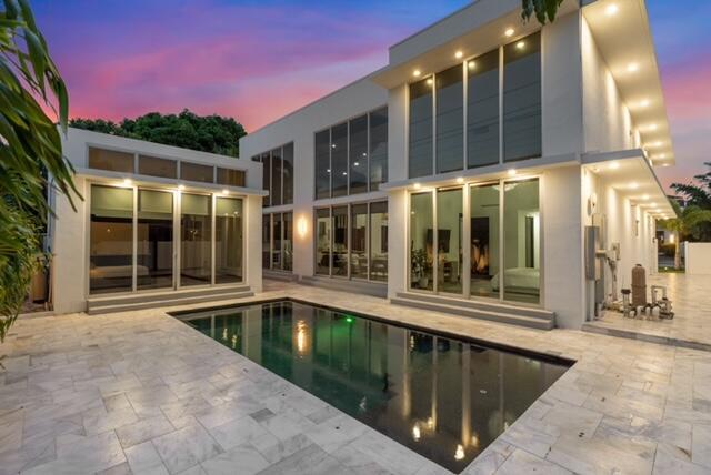 A modern two-story house with large glass windows overlooks a rectangular swimming pool and patio — 284 NE 7th Street, Boca Raton FL 33432, BOCA RATON, FL