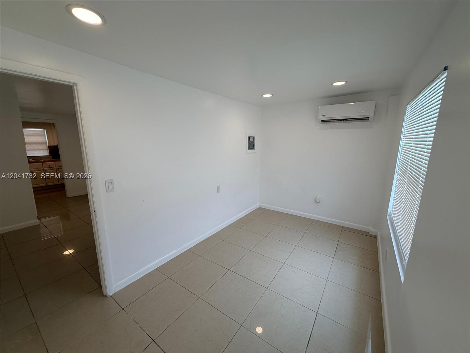 A room with light-colored tile flooring, white walls, recessed lighting, and a wall-mounted air conditioner — 548 NW 30th St # 2, Miami FL 33127, MIAMI, FL