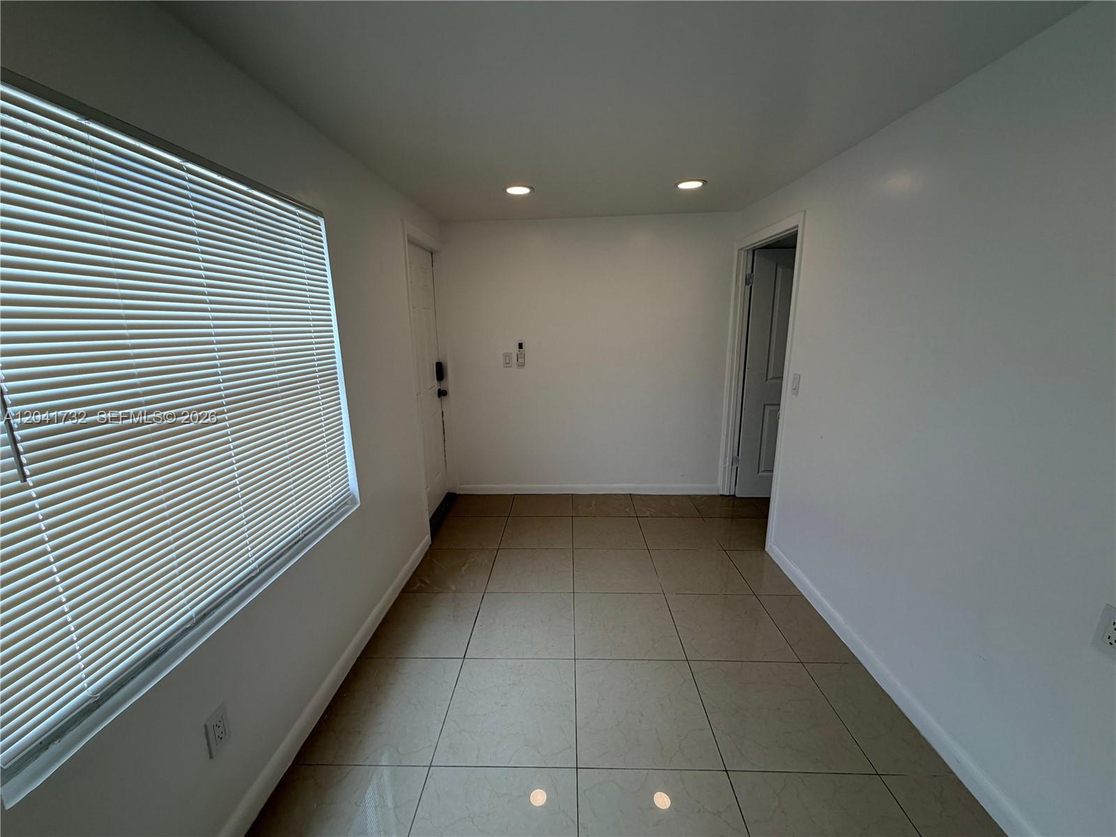 An entryway features light-colored tile flooring, white walls, a window with blinds, and recessed lighting — 548 NW 30th St # 2, Miami FL 33127, MIAMI, FL