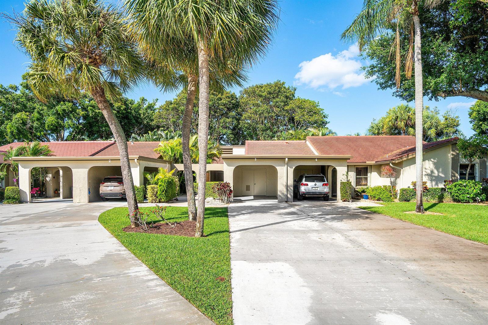 A single-story multi-unit building with covered carports, palm trees, and a concrete driveway — 5944 Forest Grove Drive # 3, Boynton Beach FL 33437, BOYNTON BEACH, FL