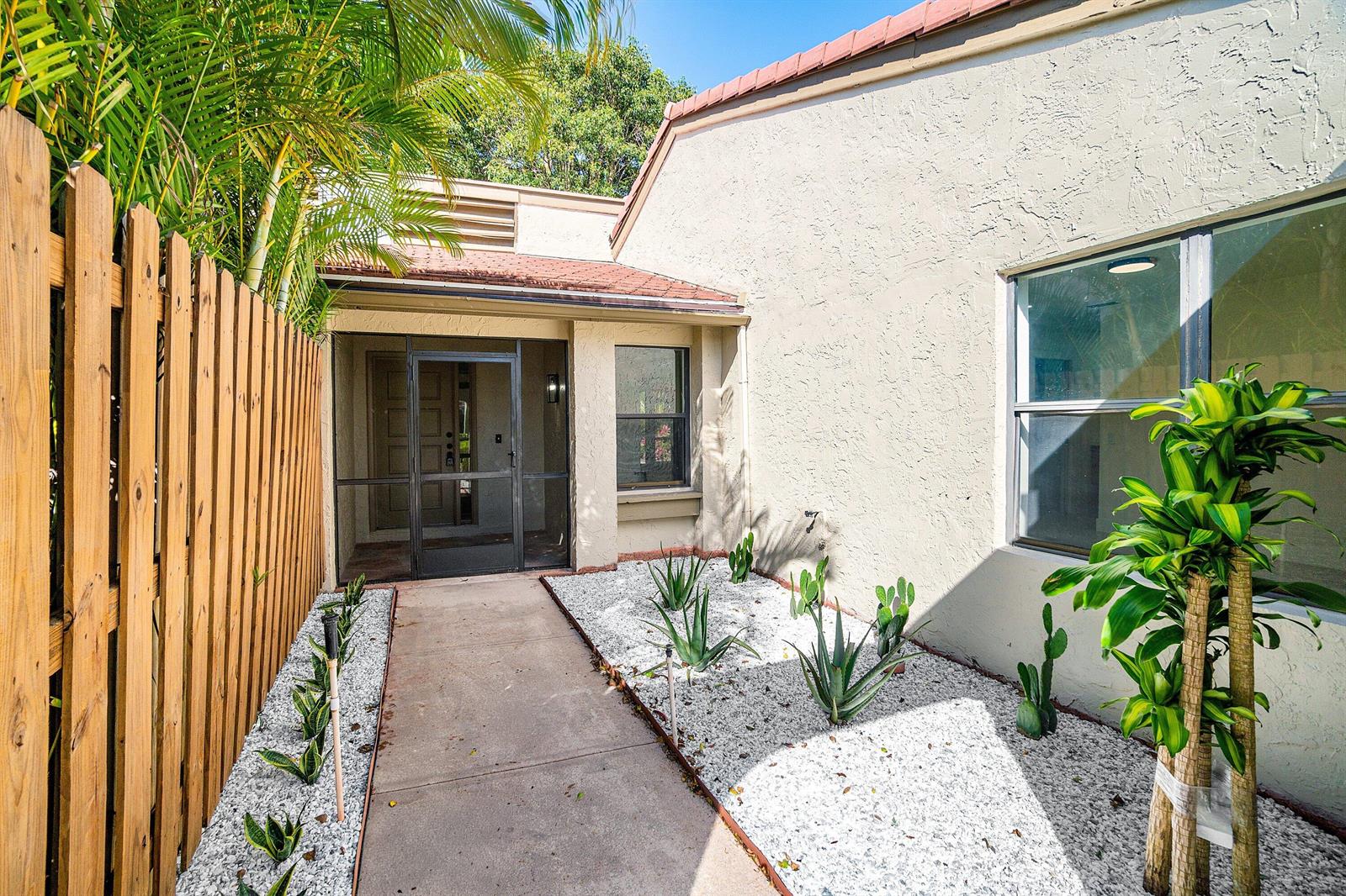 A concrete walkway leads to a screened front entryway beside a white gravel garden bed — 5944 Forest Grove Drive # 3, Boynton Beach FL 33437, BOYNTON BEACH, FL