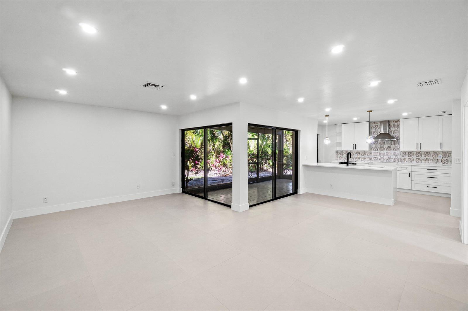 An open-concept living area with white tile floors, recessed lighting, and a modern kitchen — 5944 Forest Grove Drive # 3, Boynton Beach FL 33437, BOYNTON BEACH, FL